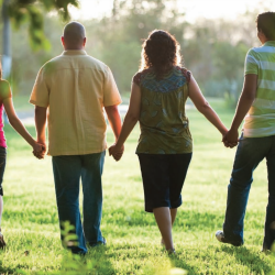 Four people walking away holding hands